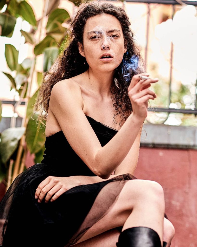 Fotografia di moda di alta gamma a Milano di Andrea Pol, con una modella elegante che posa in un abito firmato mentre fuma una sigaretta